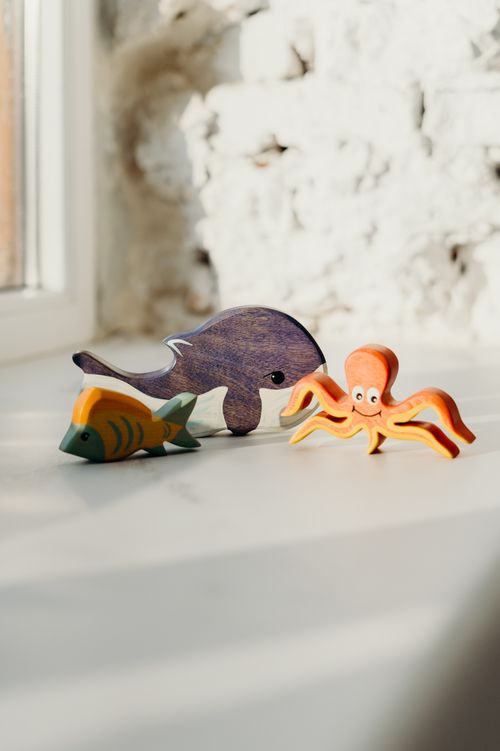 Free Playful wooden sea animal toys on a sunlit surface with a bright background. Stock Photo