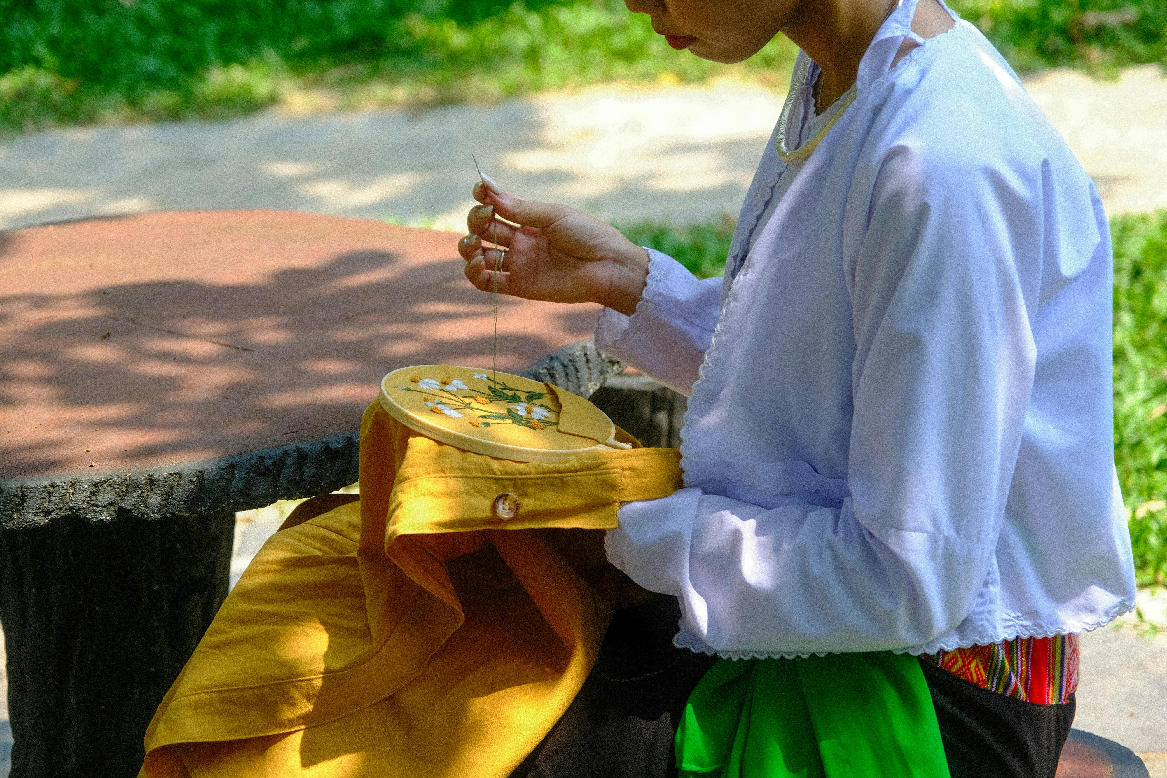 Vietnamese woman engaging in traditional embroidery outdoors in Hue, Vietnam.