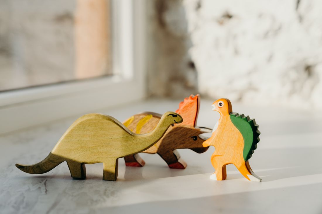 Four wooden dinosaur toys on a windowsill