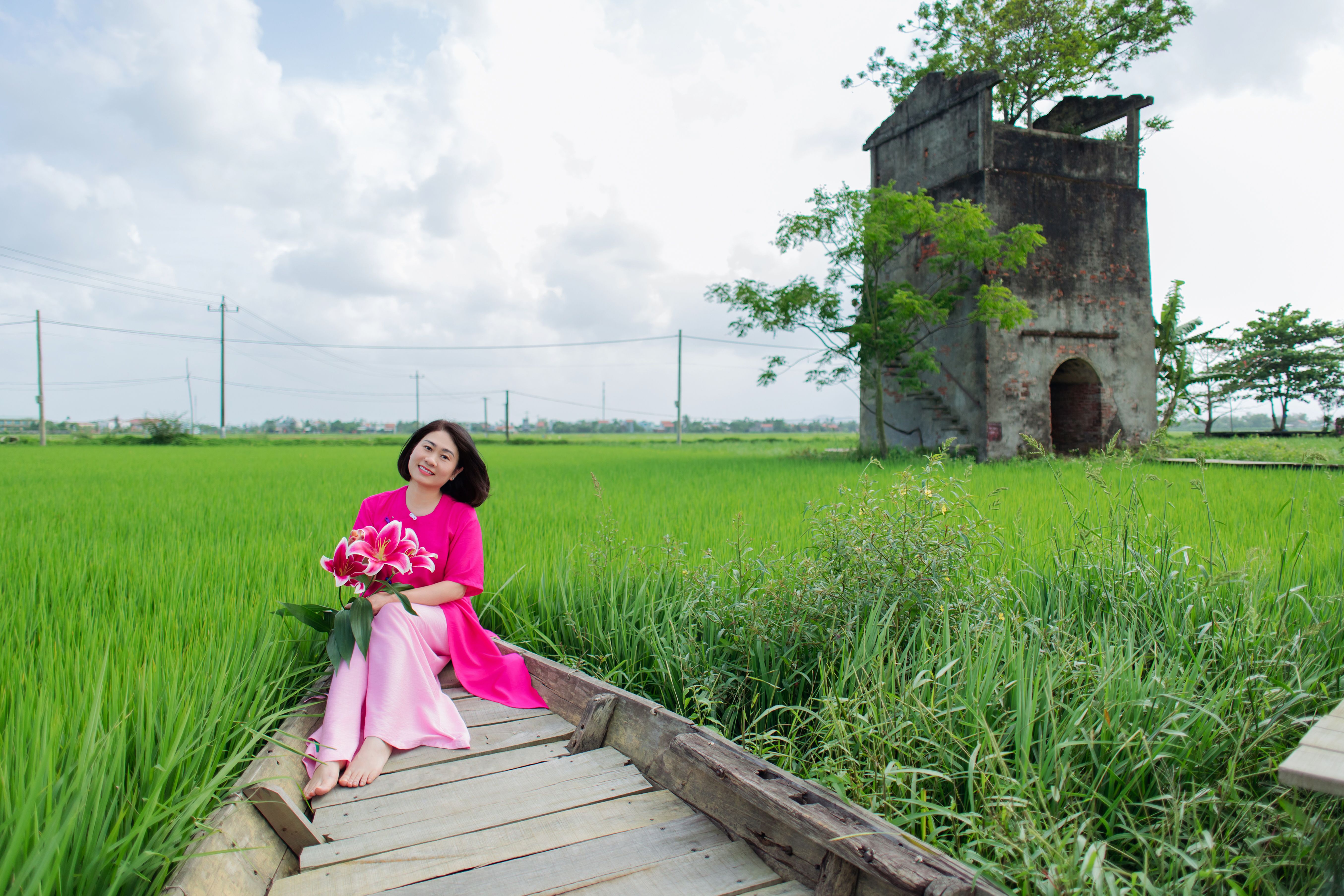 Woman in Pink Dress Holding Flowers in Green Field · Free Stock Photo