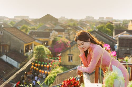 Free A woman in traditional attire enjoys a vibrant rooftop view in Hoi An, Vietnam. Stock Photo