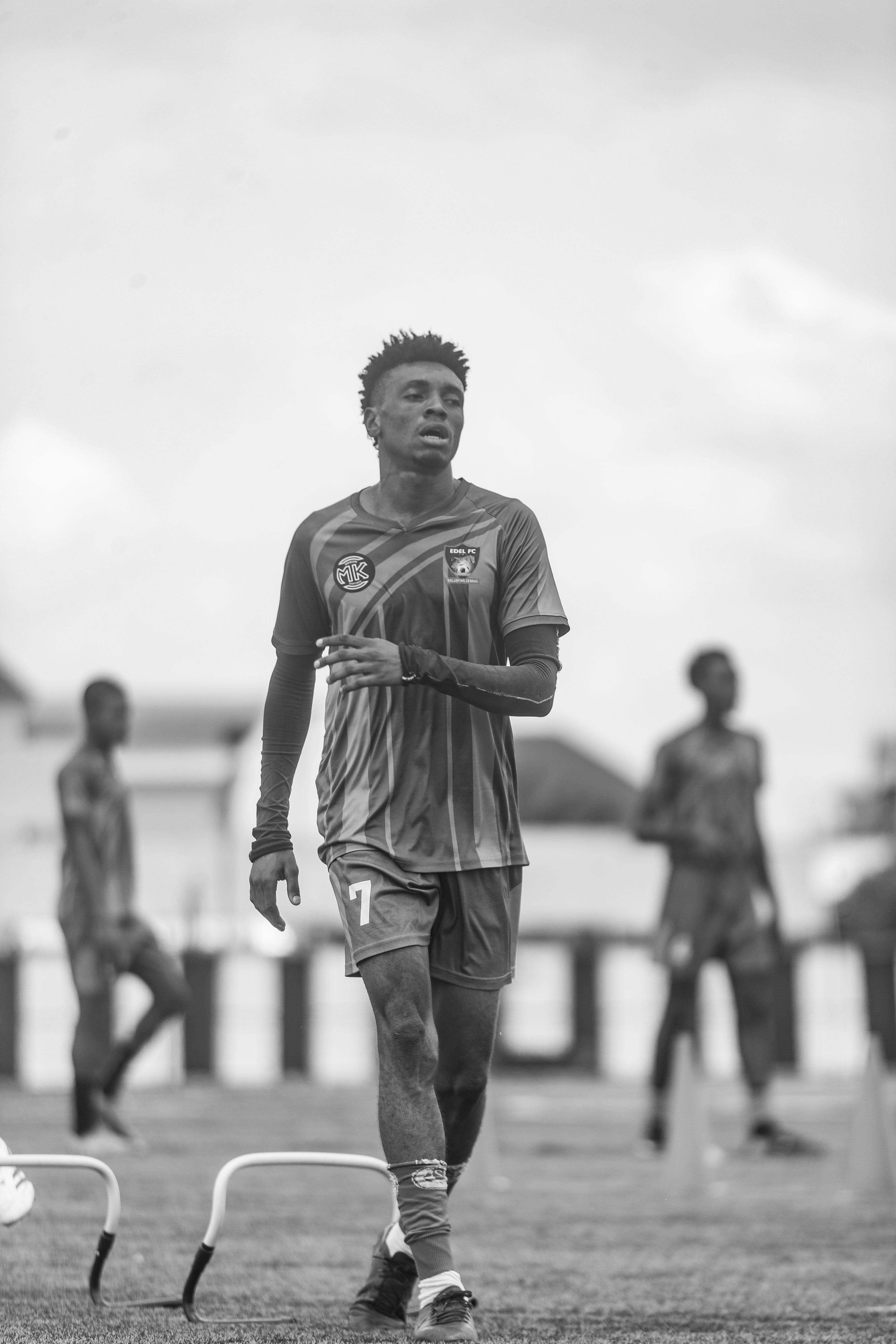 Black and white image of soccer players in training on a field.