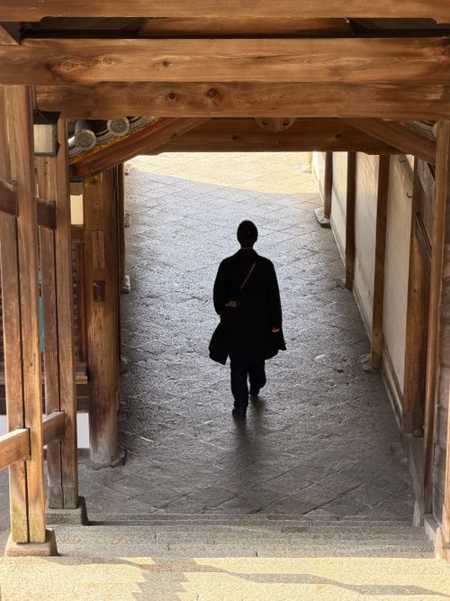 Free Silhouette of a person walking through a wooden corridor in a Japanese temple. Stock Photo