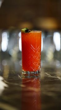 Vibrant red cocktail in a decorative glass on a marble counter, perfect for nightlife settings.