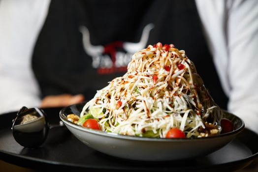 Vibrant bowl of coleslaw with cherry tomatoes, nuts, and sauce, perfect for healthy dining.