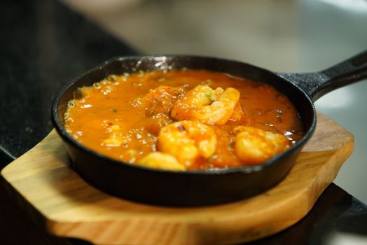 Delicious shrimp simmering in rich tomato sauce in a cast iron skillet.
