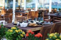 Wooden table with diverse breakfast spread in an outdoor restaurant setting.