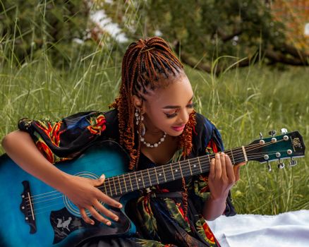 A woman enjoying playing guitar in a sunlit meadow, evoking a sense of peace and creativity.