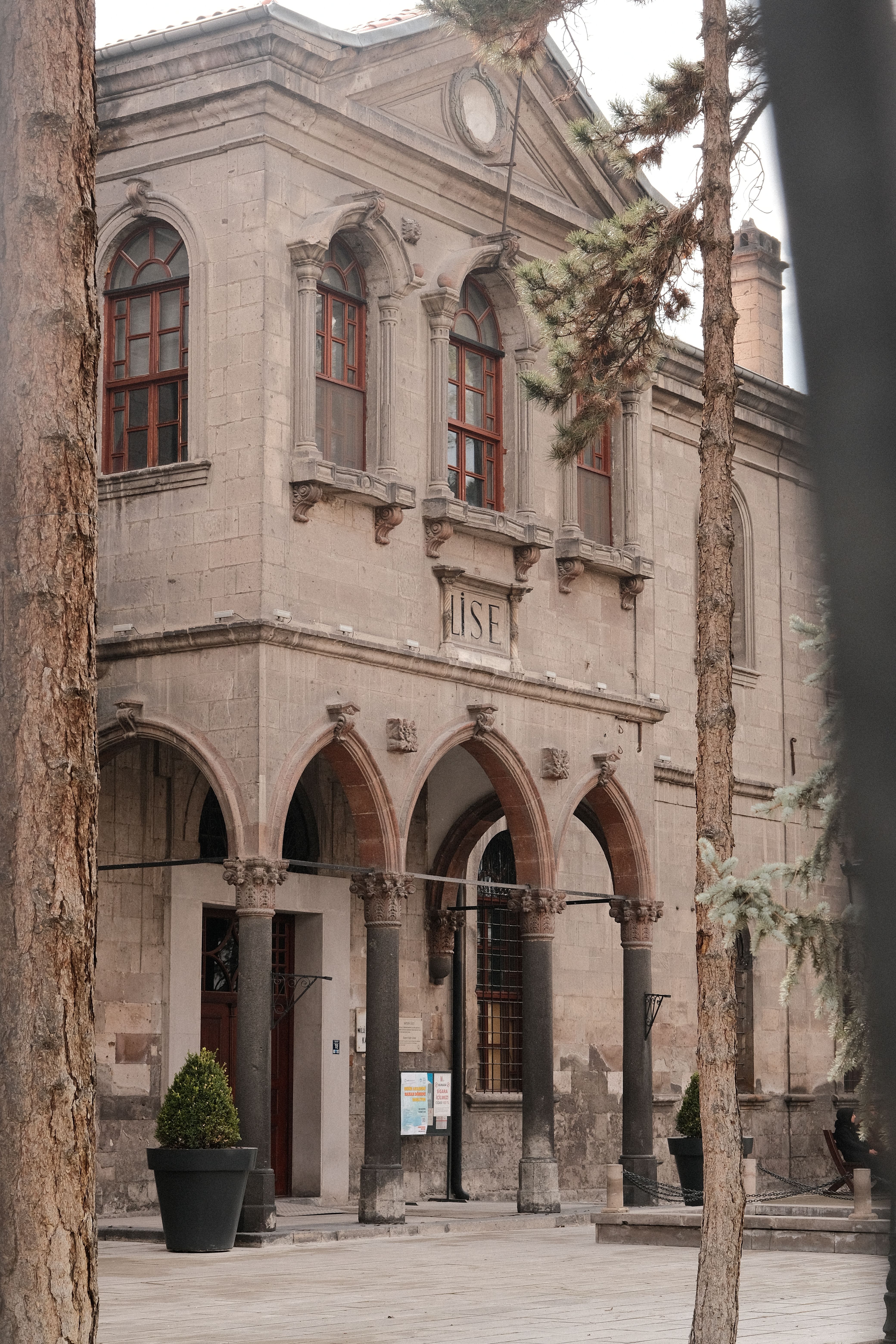 A beautiful historic stone building with arches, framed by tall trees, suggesting a serene atmosphere.