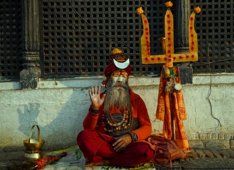 A holy Sadhu sits in vibrant attire during a spiritual moment in Kathmandu, Nepal.