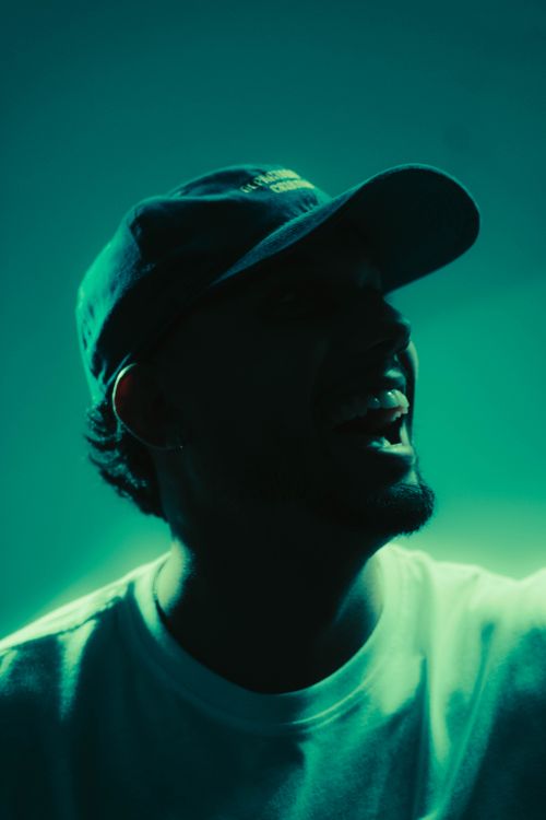 Free Artistic silhouette of a man wearing a cap, illuminated by green light, evoking mystery and intrigue. Stock Photo