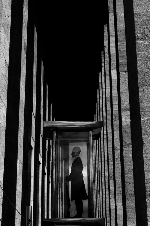 Free Black and white silhouette of a person within tall columns, creating dramatic shadows. Stock Photo
