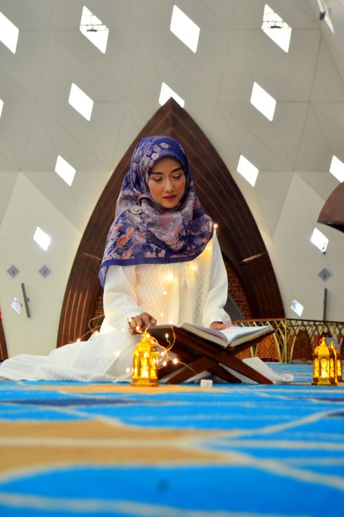 Free A woman wearing a headscarf reads the Quran inside a mosque in Bandung. Stock Photo