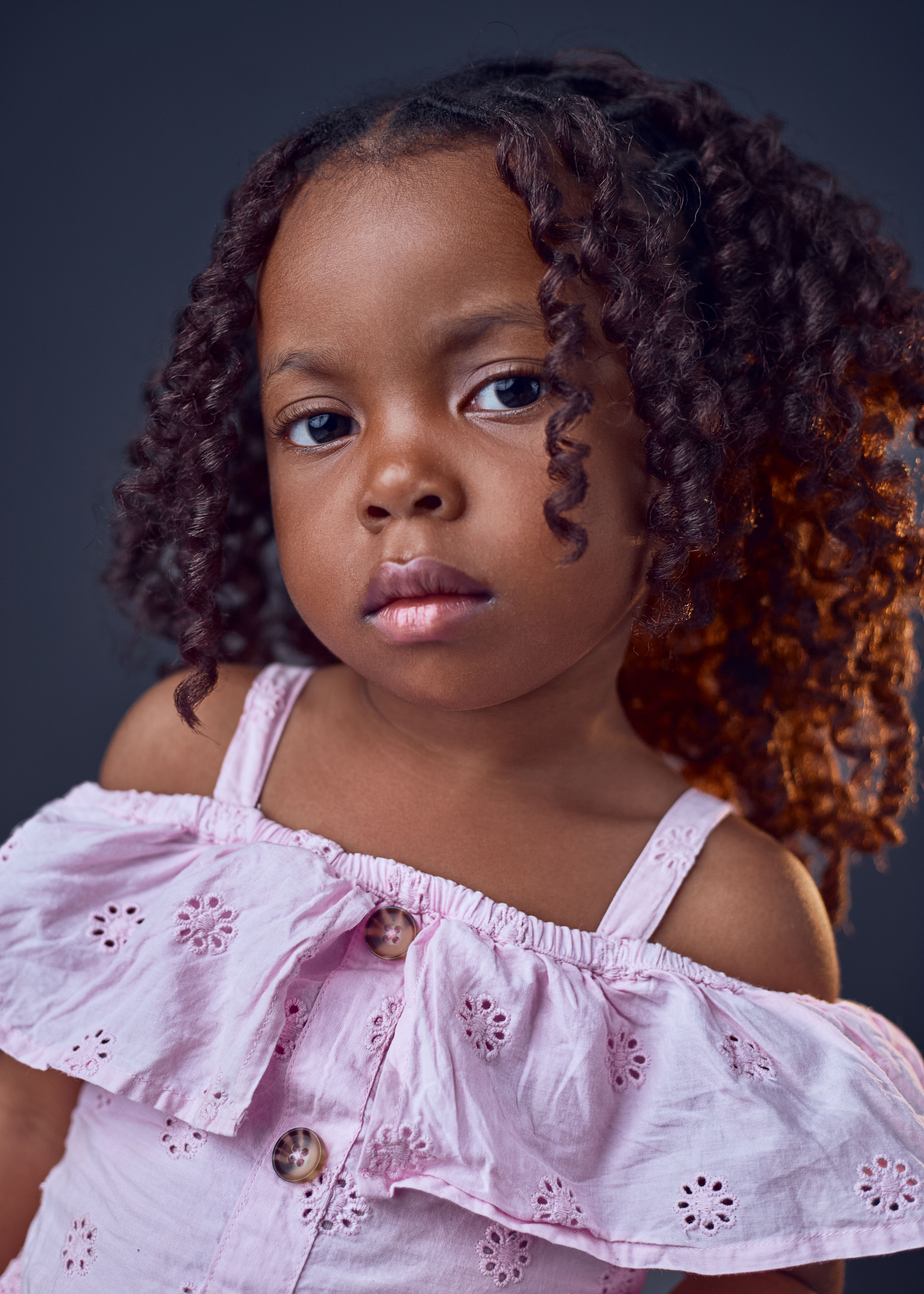Charming portrait of a young girl with curly hair in Kumasi, Ghana.