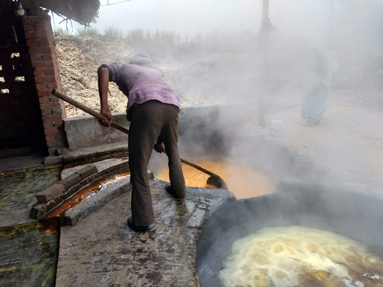 Man  Holding Brown Wooden Stick Working On Hot Liquid