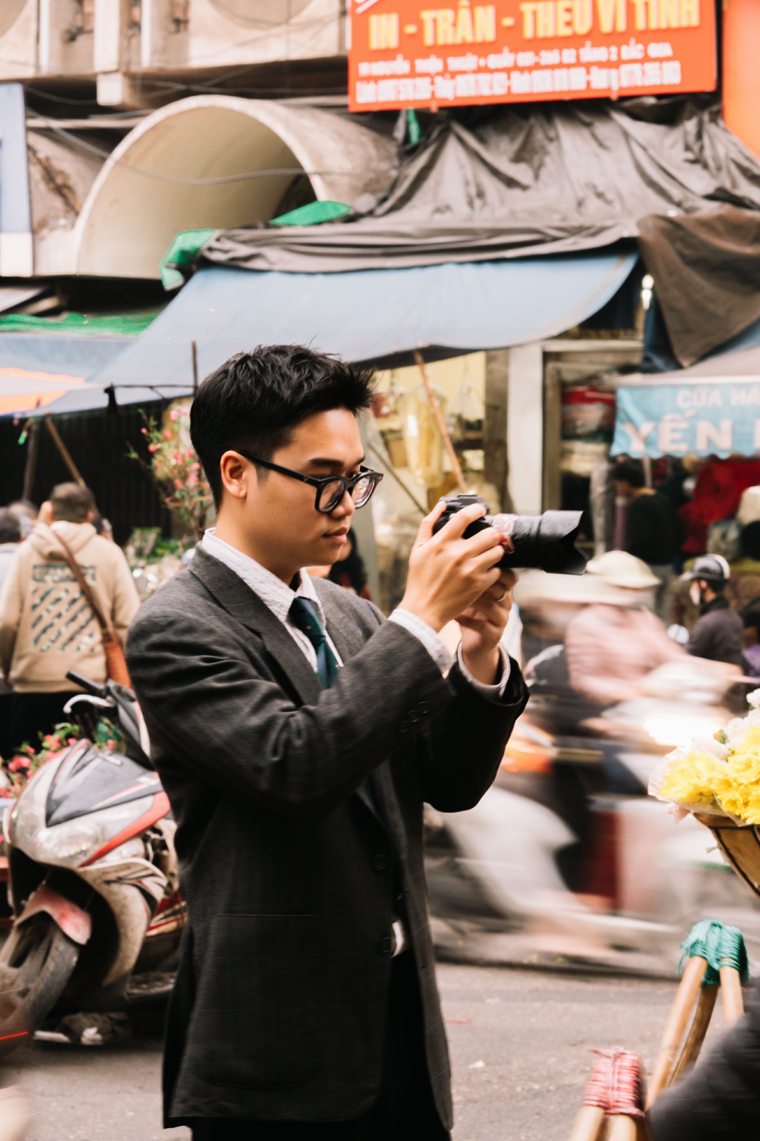 Elegant man photographing a bustling market, capturing dynamic street life.