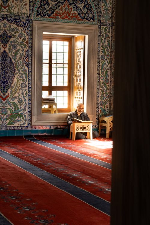 Free Elderly man reading by a sunlit window in a beautifully decorated mosque in Ankara, Türkiye. Stock Photo