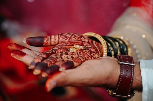 Free Close-up of henna-adorned hands holding rings, signifying engagement or marriage ceremony. Stock Photo