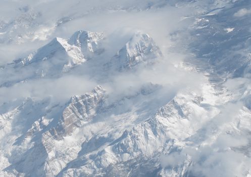 Breathtaking aerial shot of snowy peaks in the Swiss Alps during winter, enveloped in clouds. 36635184