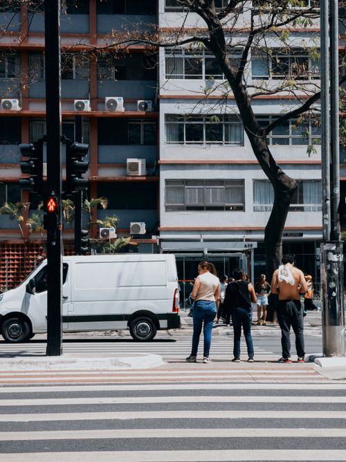 Free People crossing a street in São Paulo during the day, with urban architecture backdrop. Stock Photo