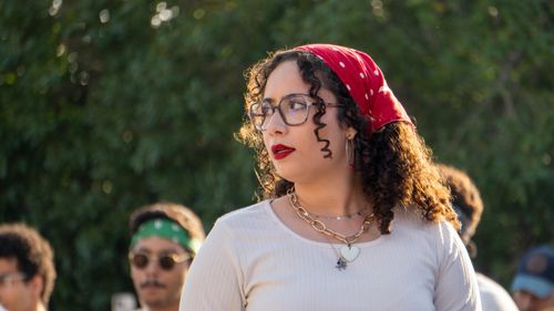 Free A woman wearing a red bandana looking sideways in an outdoor setting, exuding confidence and style. Stock Photo
