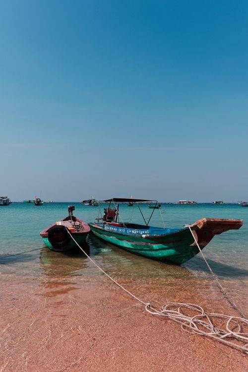 Free Traditional wooden boats docked on the tranquil shores of Phu Quoc, Vietnam under a clear blue sky. Stock Photo