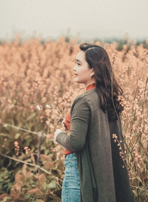 Free A serene moment of a young woman standing in a blooming field, embracing nature's beauty. Stock Photo
