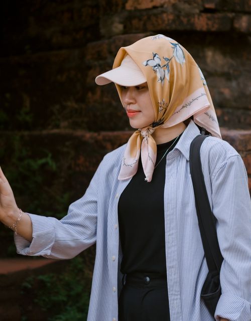 Free A fashionable young woman in a floral headscarf and casual outfit, captured outdoors, exuding elegance. Stock Photo