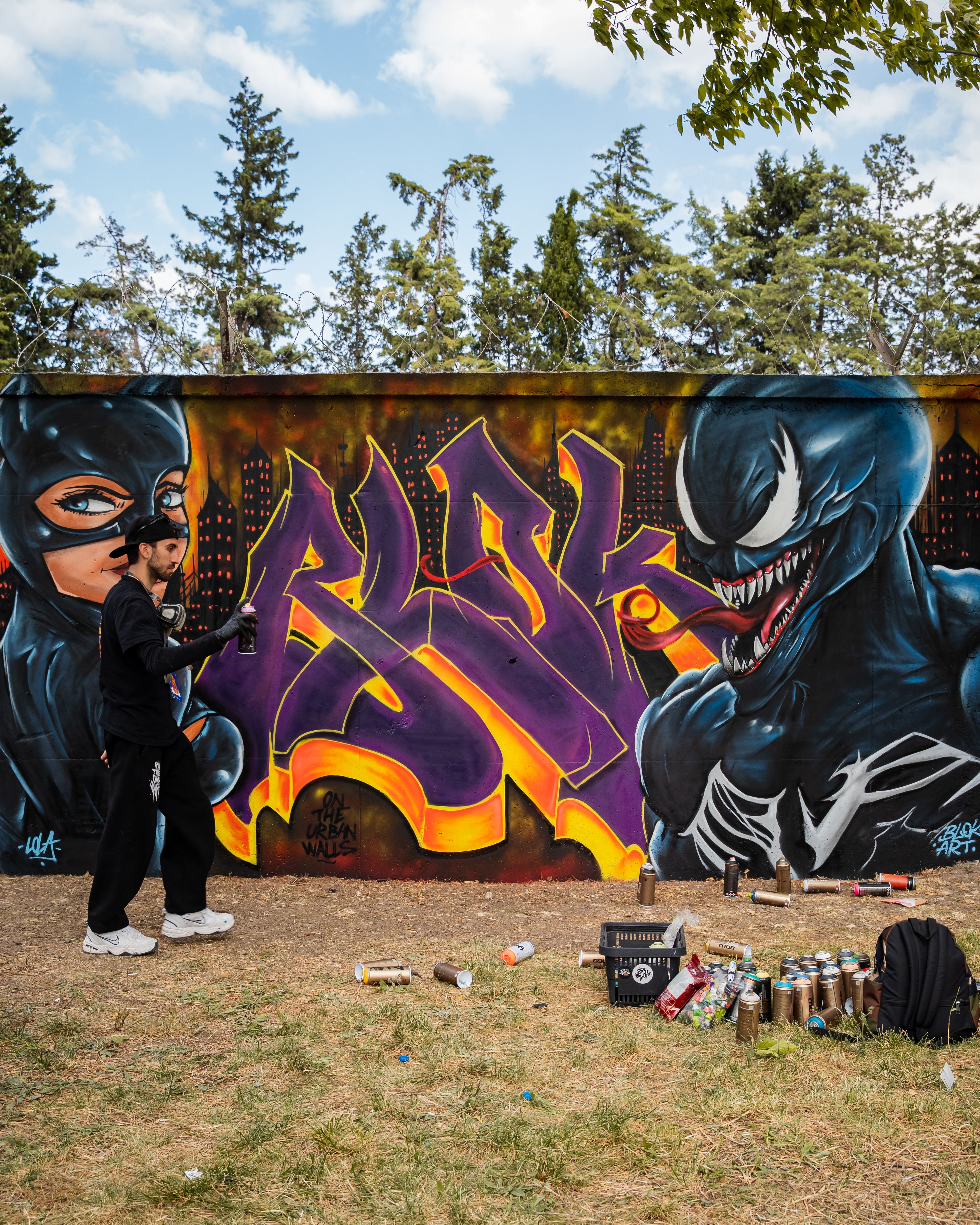 Street artist paints a dynamic graffiti mural featuring vibrant colors and comic characters.