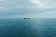 Solitary Cargo Ship on Calm Ocean under Cloudy Sky