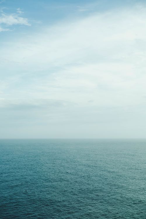 Free Serene ocean view with a vast expanse of blue sky captured on a clear day. Stock Photo