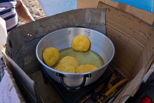 Close-up of sopapillas frying in a pan at a street market in La Serena, Chile.