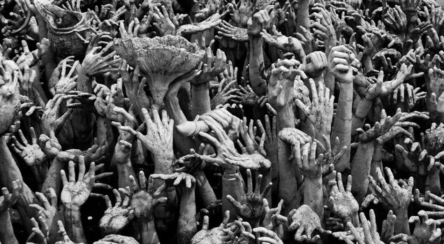 Intricate sculpture of reaching hands at Wat Rong Khun, symbolizing human suffering and desire.