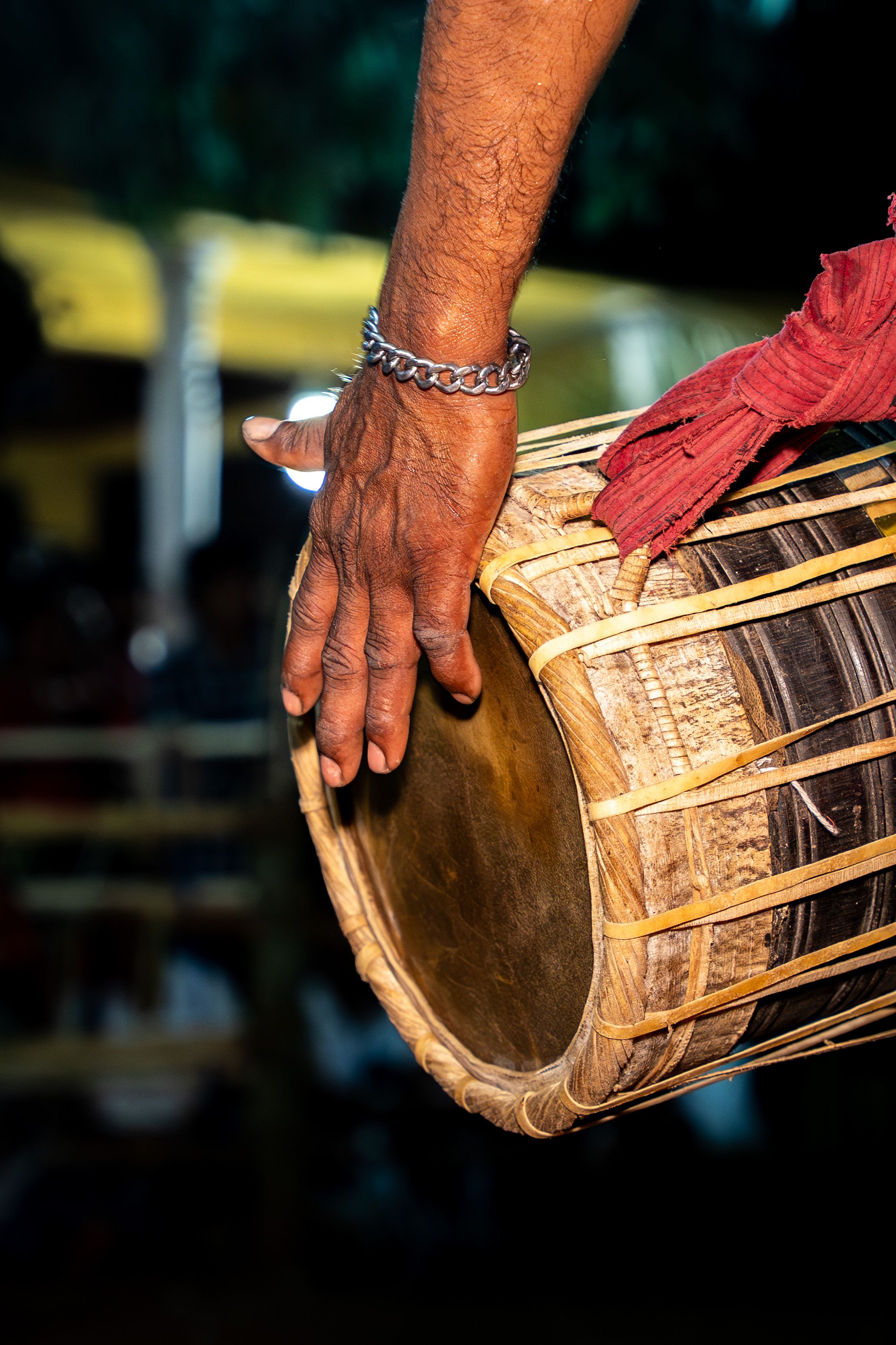 Close-up of a hand playing a Sri Lankan traditional drum at night, capturing cultural essence.