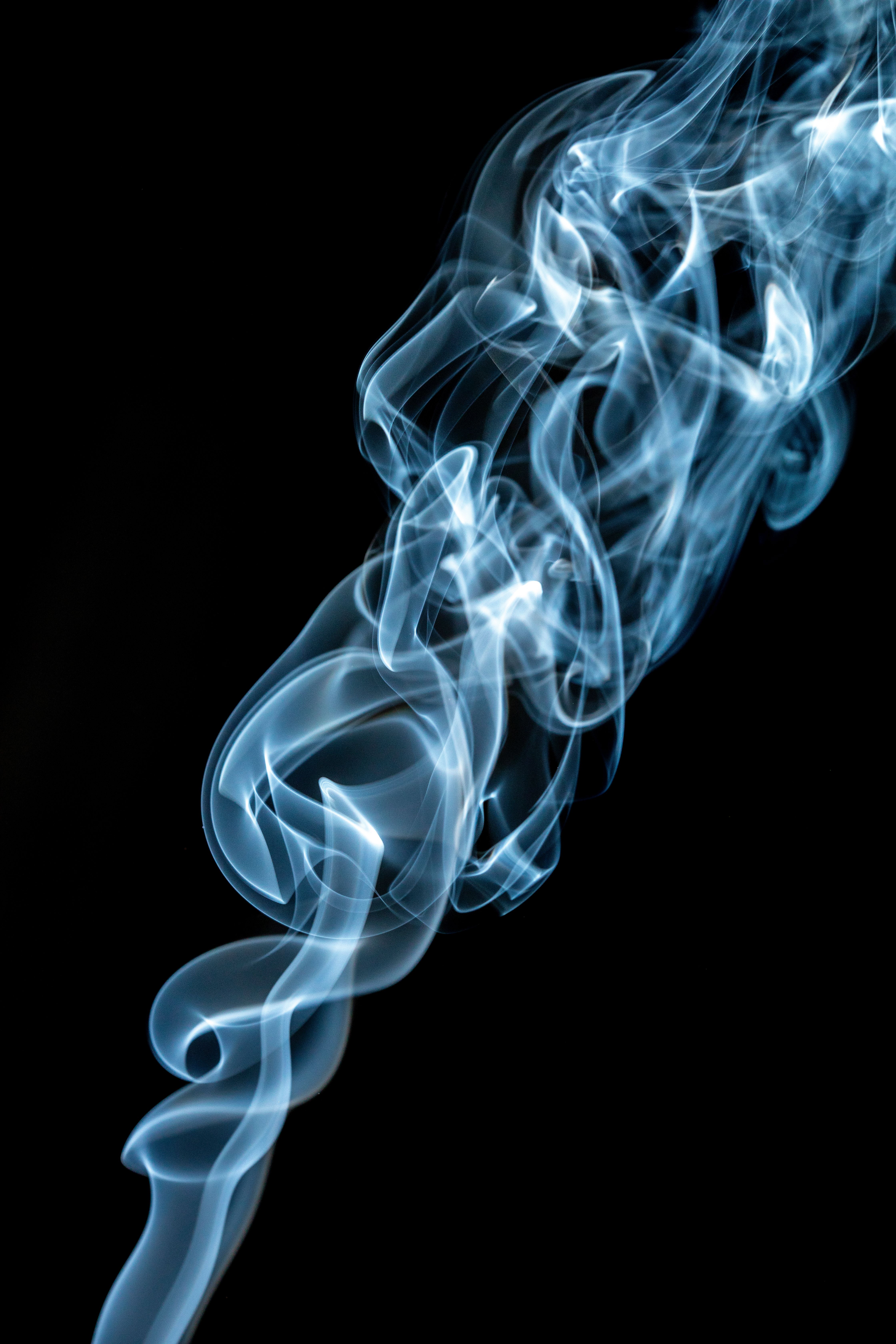 Elegant swirls of blue smoke create an artistic pattern against a deep black background.
