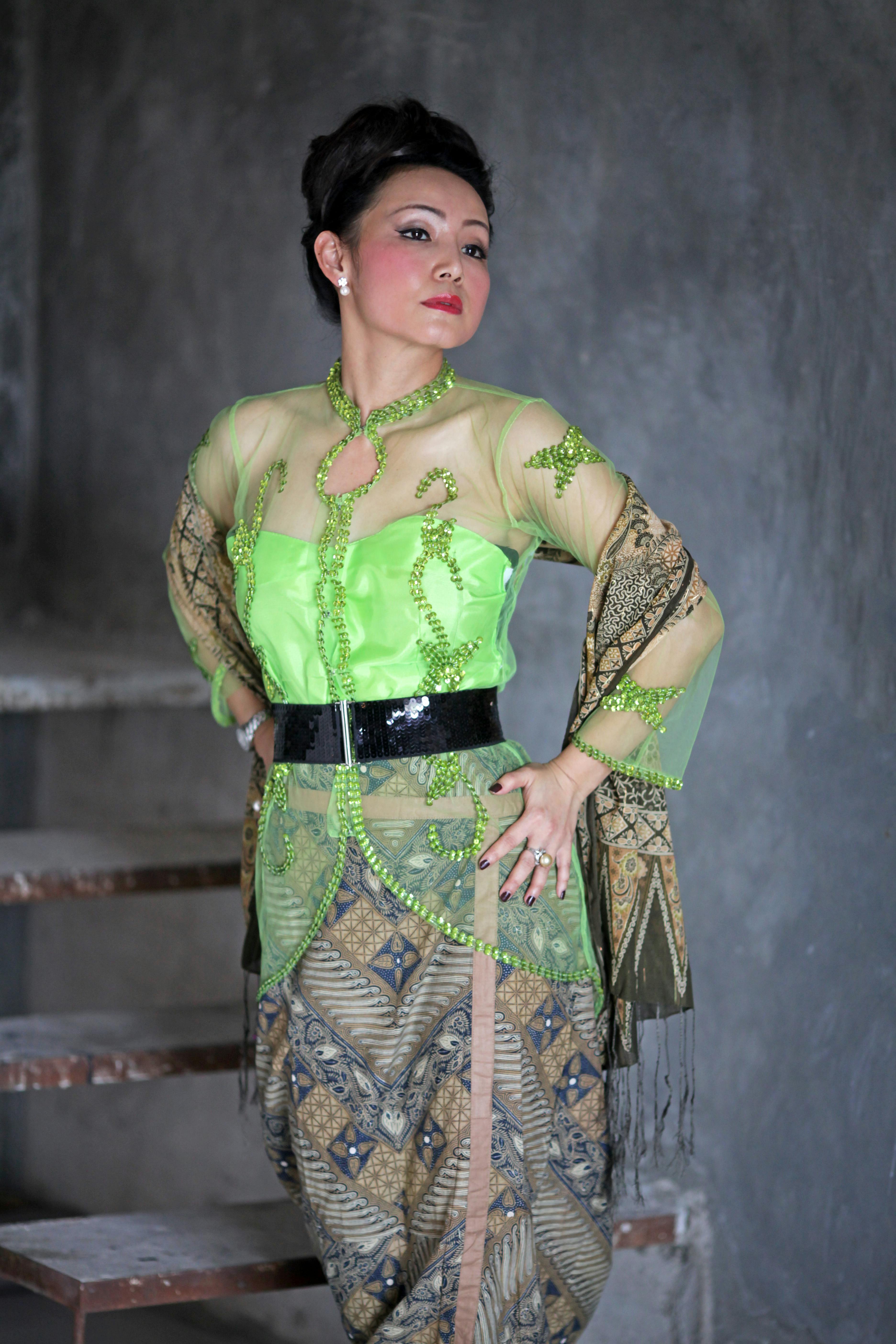 Stunning portrait of a woman in a vibrant green Indonesian Kebaya, showcasing traditional fashion.