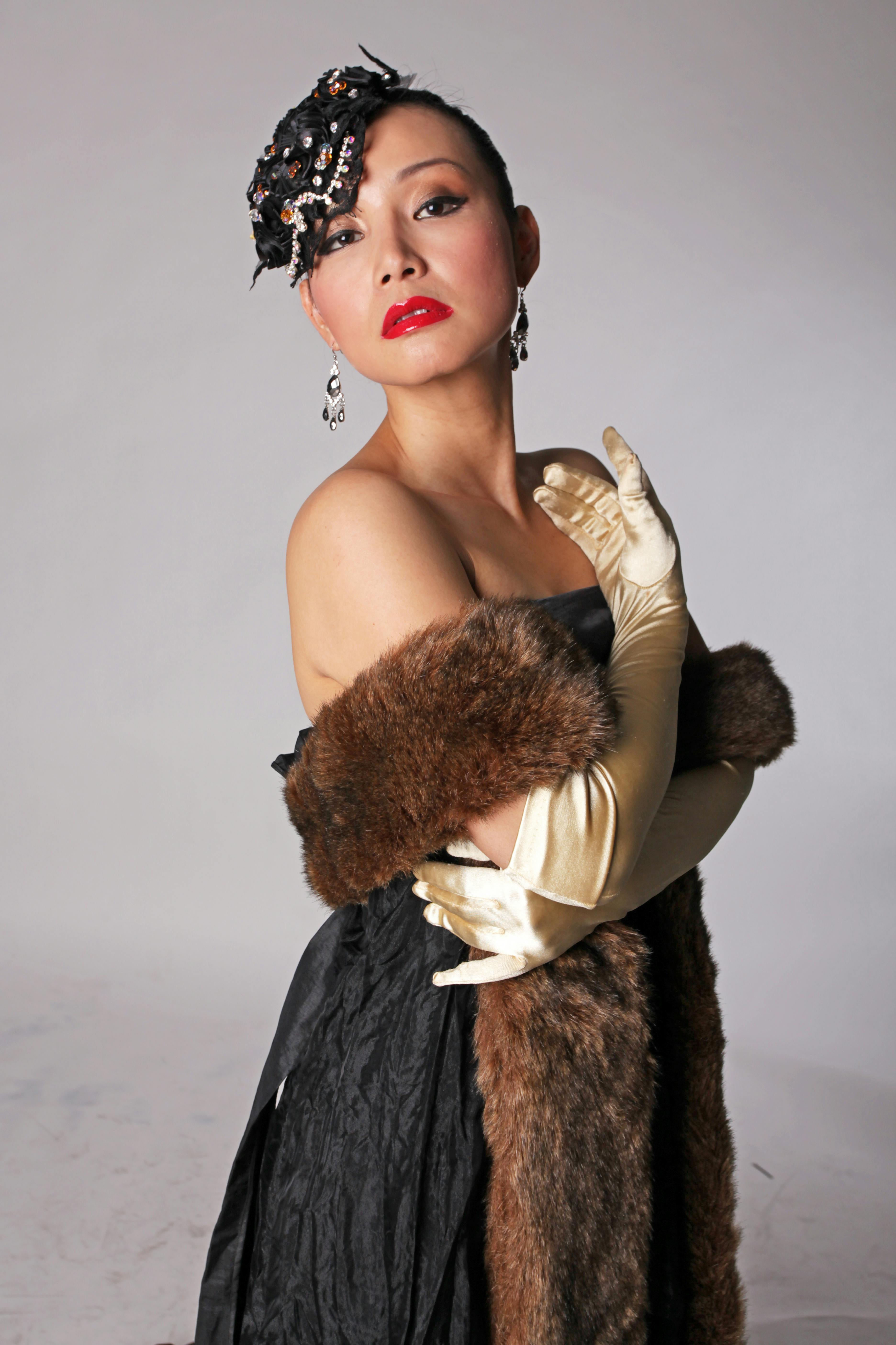 Stylish woman in vintage attire with gloves and fur wrap, exuding elegance.