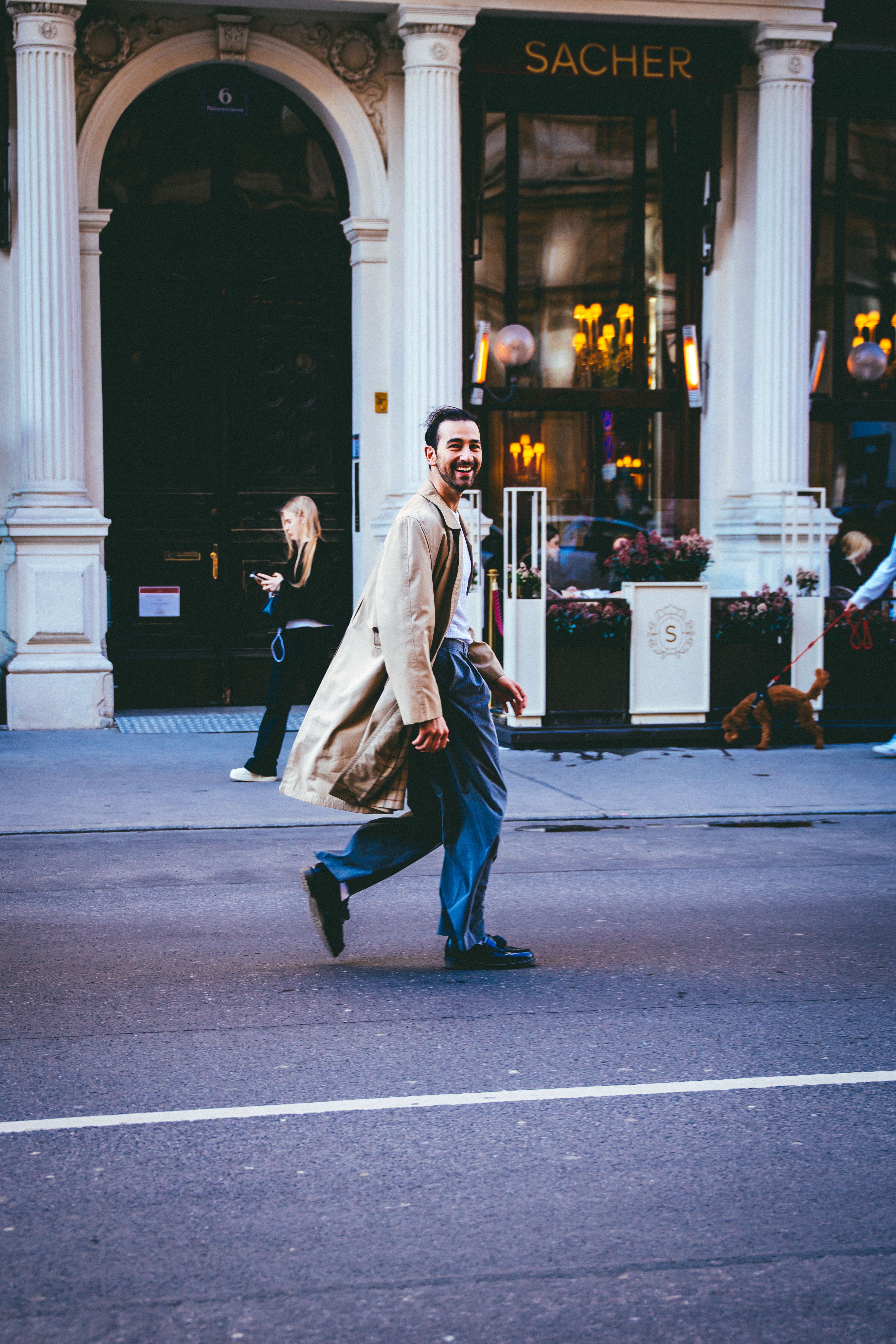 Casually dressed man crossing the street near famous Hotel Sacher, Vienna, Austria.