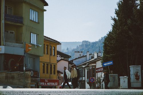 Free View of pedestrians crossing a street in Kütahya, Türkiye with historical buildings and distant hills. Stock Photo