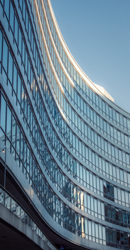 Modern curved glass building facade in Manchester, United Kingdom at sunset.