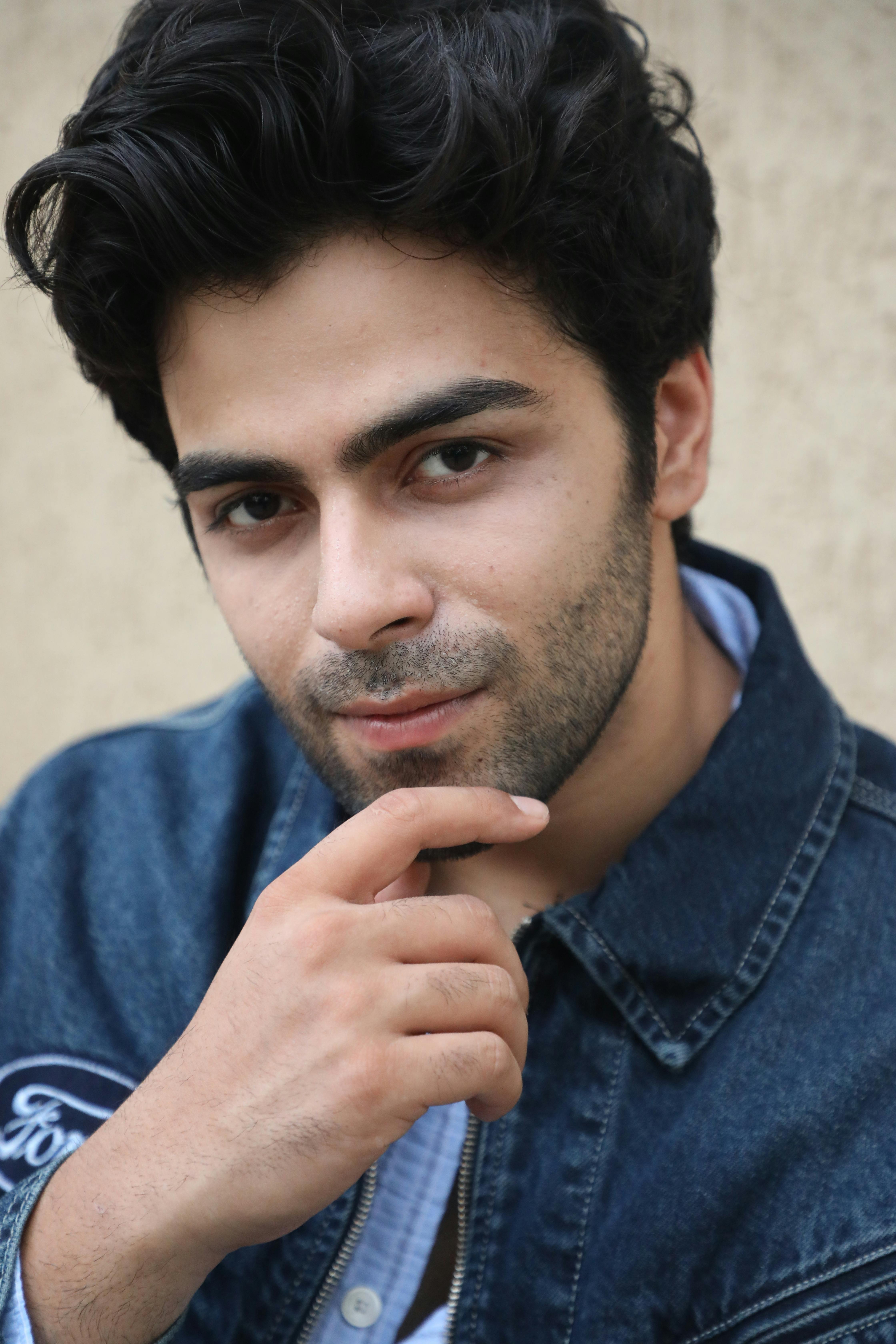 Close-up portrait of a young man in denim, with a thoughtful expression.