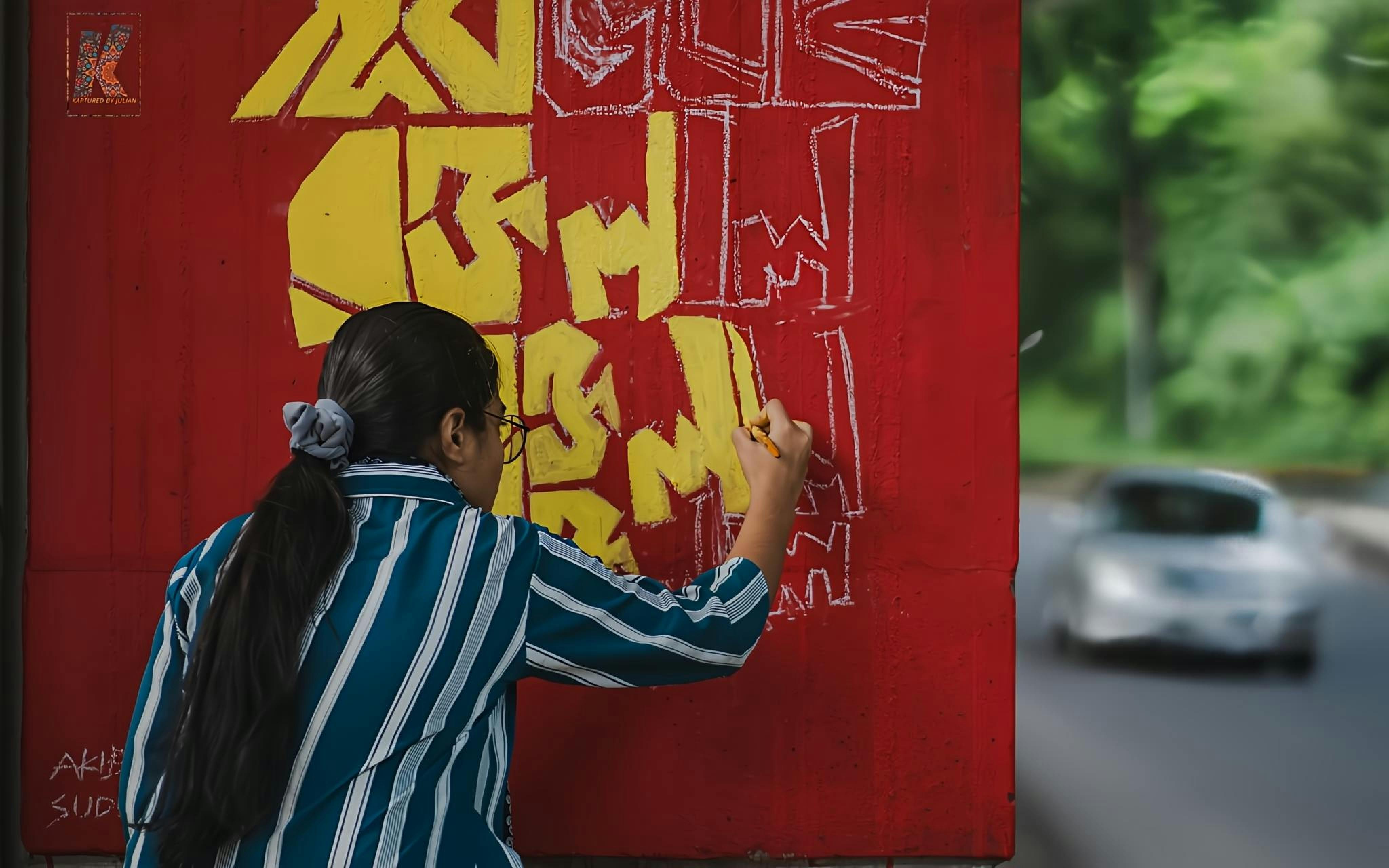 Artist painting geometric mural on a city wall, vibrant colors, urban setting.