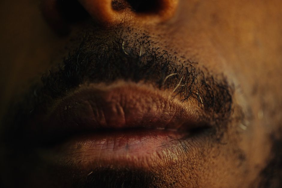 Detailed close-up of a man's lips and mustache with a focus on texture.