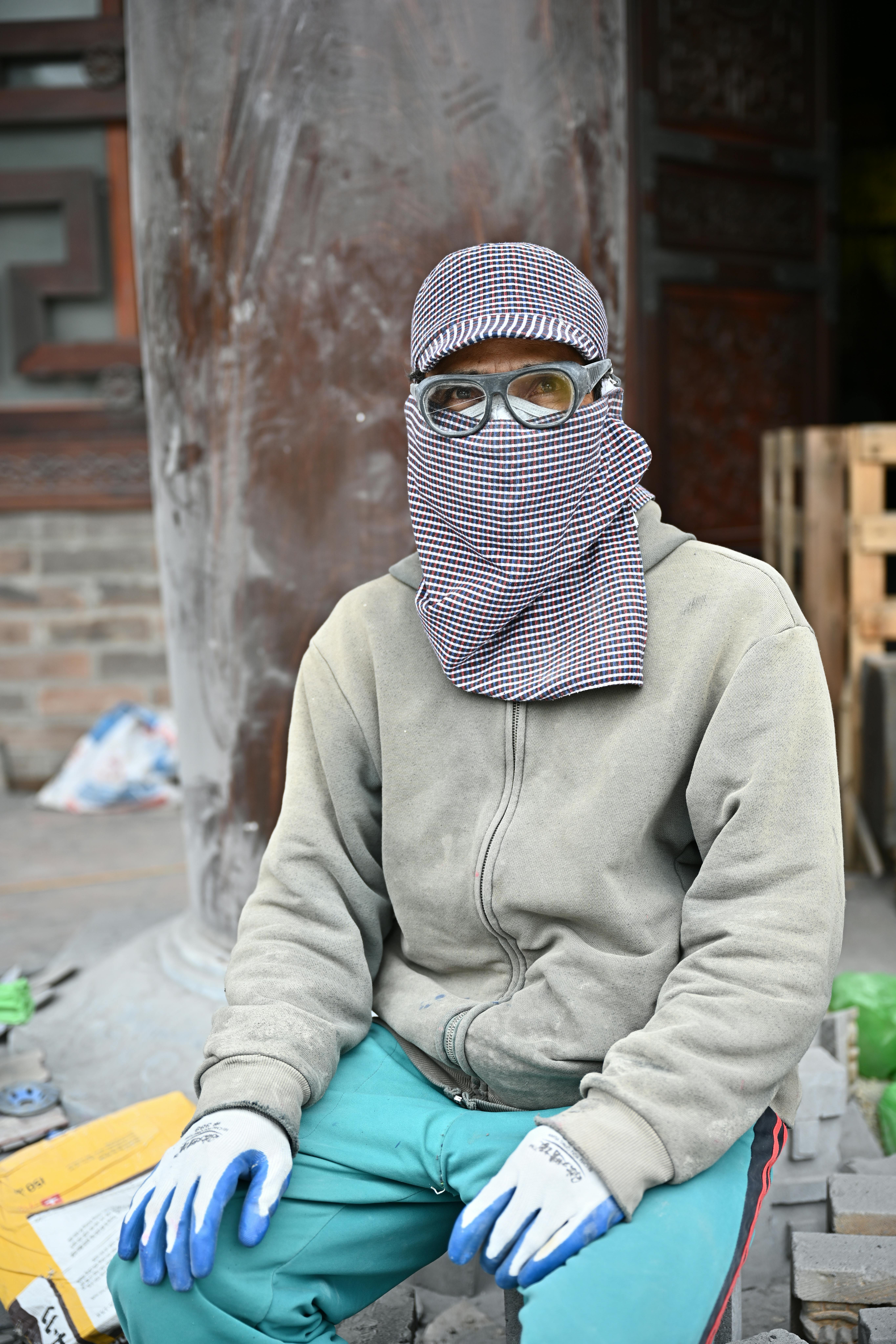 A worker with face covered sits at a temple restoration site in Kim Bảng, Vietnam.