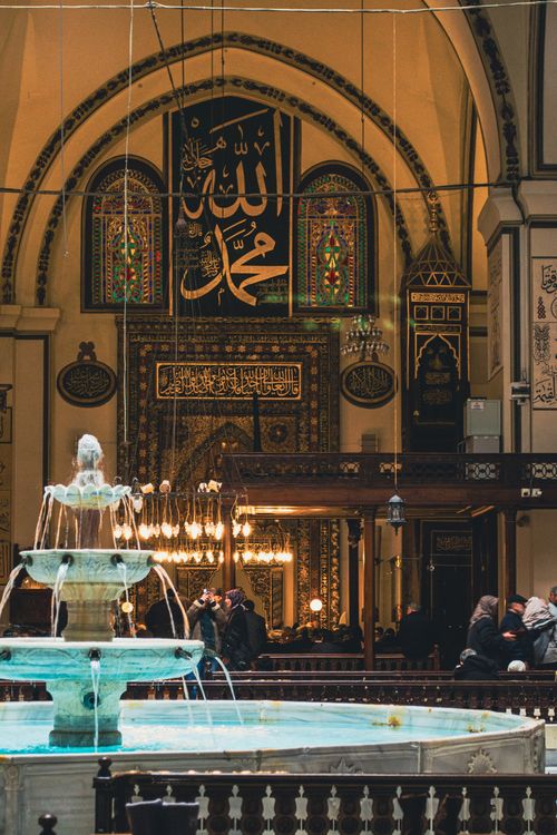 Free A stunning view inside the iconic Grand Mosque featuring intricate Arabic calligraphy and a central fountain. Stock Photo