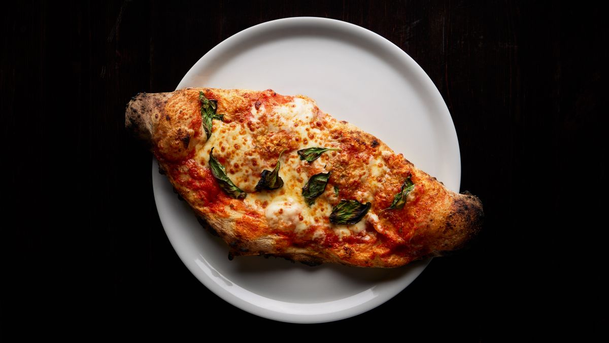 Freshly baked calzone with melted mozzarella and basil