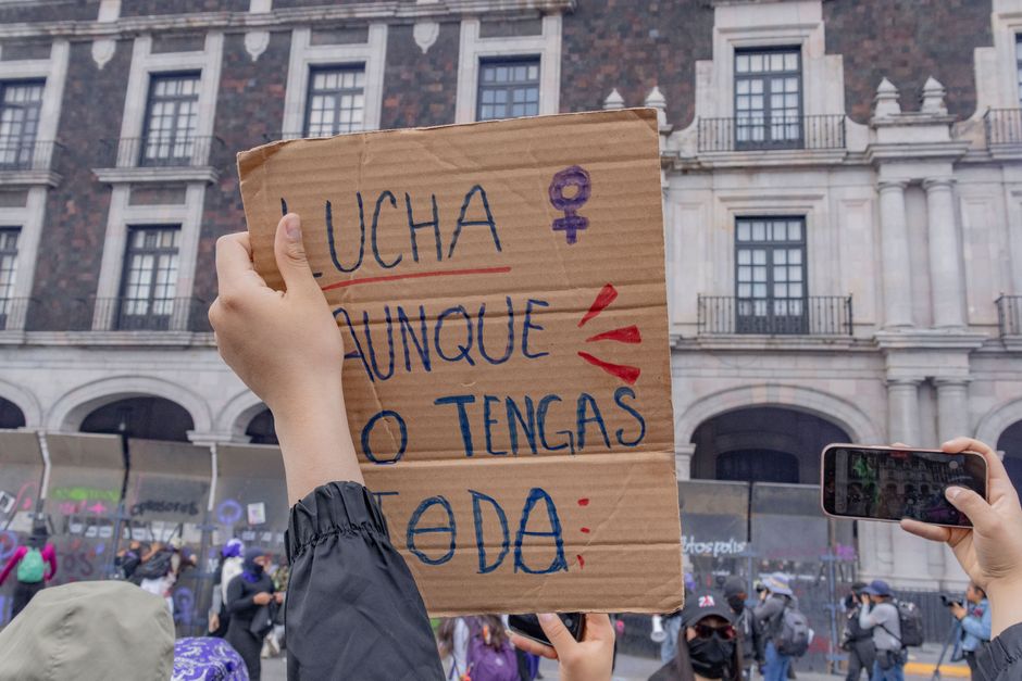 Una protesta feminista con diversos participantes sosteniendo un cartel que dice 'Lucha aunque no tengas todo'.