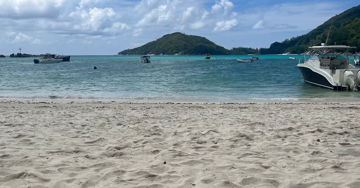 Idyllic sandy beach with boats in the turquoise waters of Seychelles.