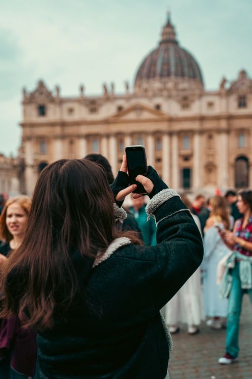 Free A tourist taking a photo of St. Peter's Basilica in Vatican City on a clear day. Stock Photo
