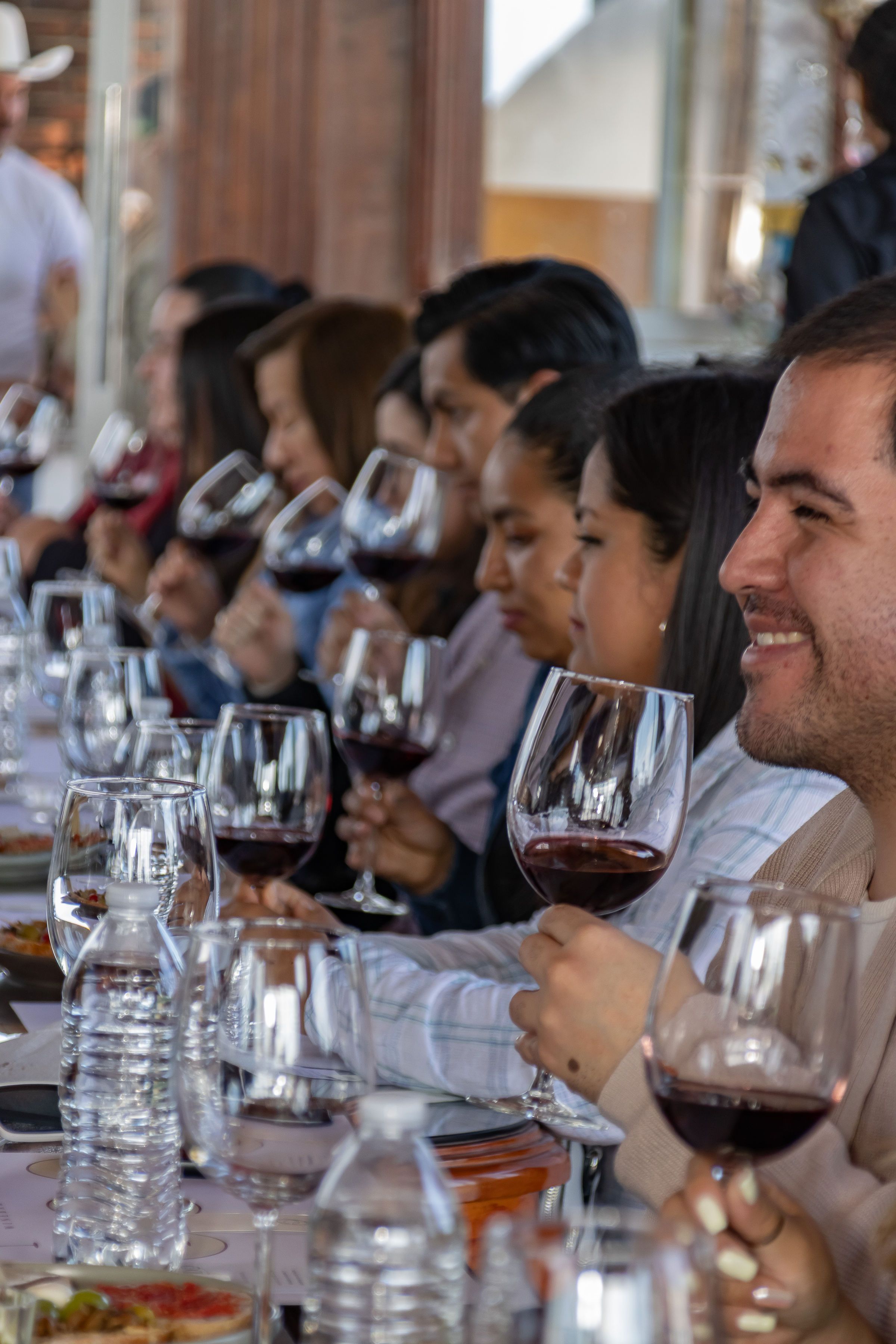 A long table of guests raising glasses of red wine side by side